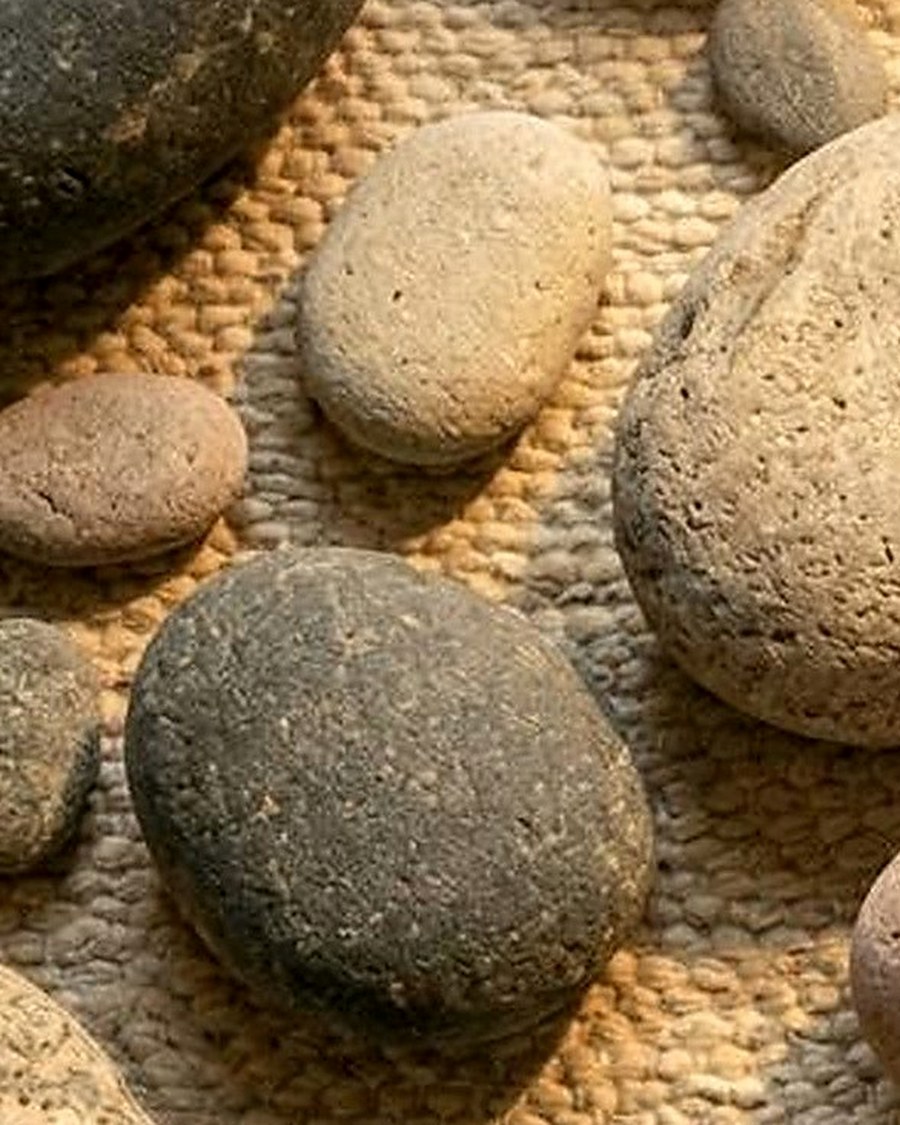 Close-up of rounded stone forms on warm woven fabric